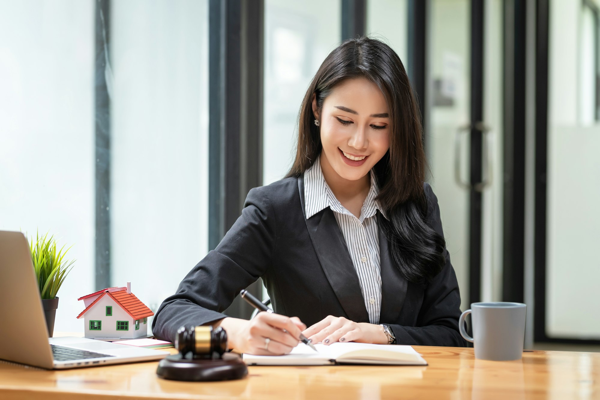 Front view of young Asian businesswoman or lawyer holding pen to note real estate consulting idea